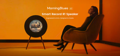 Person sitting in a chair next to a smart record R1 bluetooth turntable speaker with 'MorningBlues' branding on an orange background.